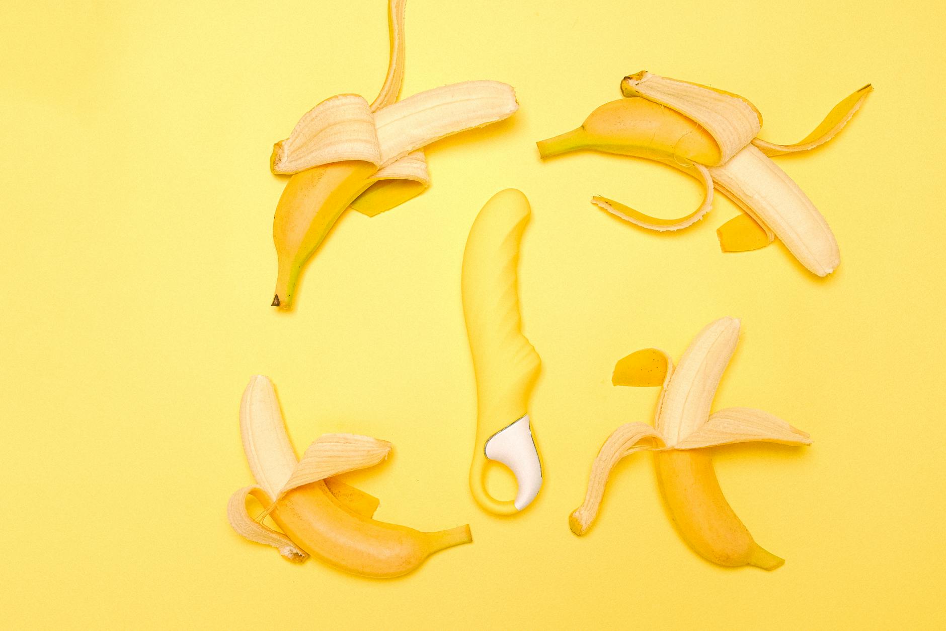 A lemon clitoral vibrator surrounded by fresh lemons on a bright yellow background