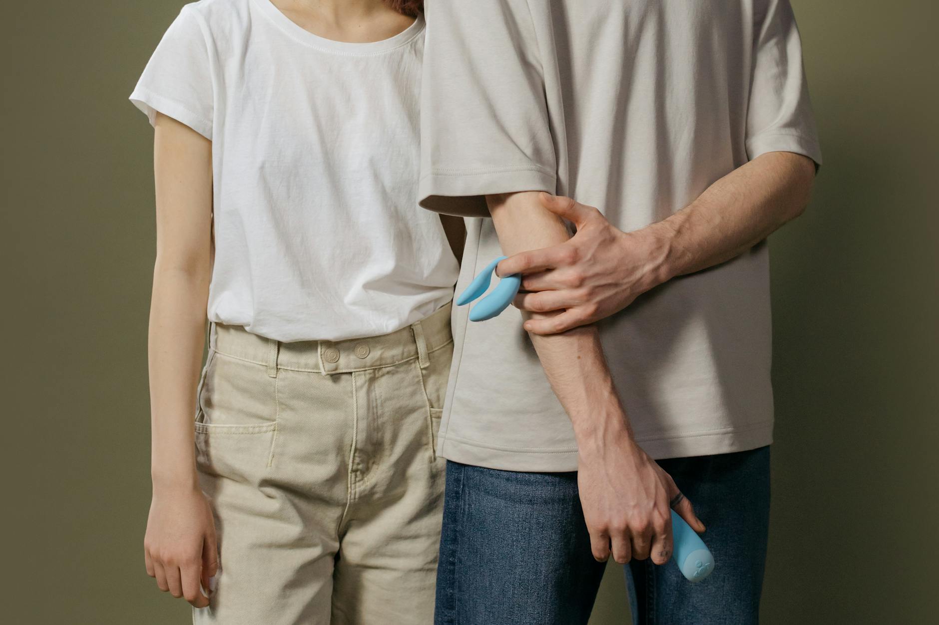 A couple holding a blue vibrator together, representing modern intimacy and connection across distance